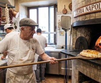 Kucharz wyjmuje tradycyjną pizzę calzone z pieca.