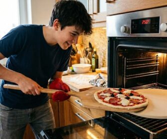 Chłopak wkłada pizzę na kamień w rozgrzanym piekarniku.