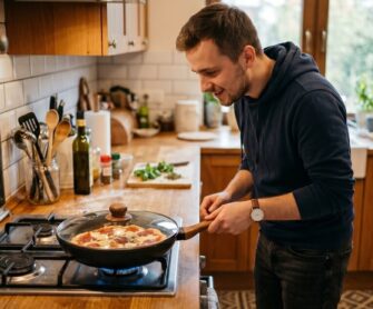 Chłopak przygotowuje pizzę na patelni.