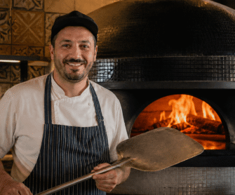 Pizzaiolo pokazuje najlepszą łopatę do pizzy.
