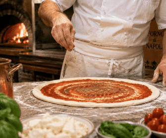 Pizzaiolo posypuje pizzę przyprawami i ziołami.